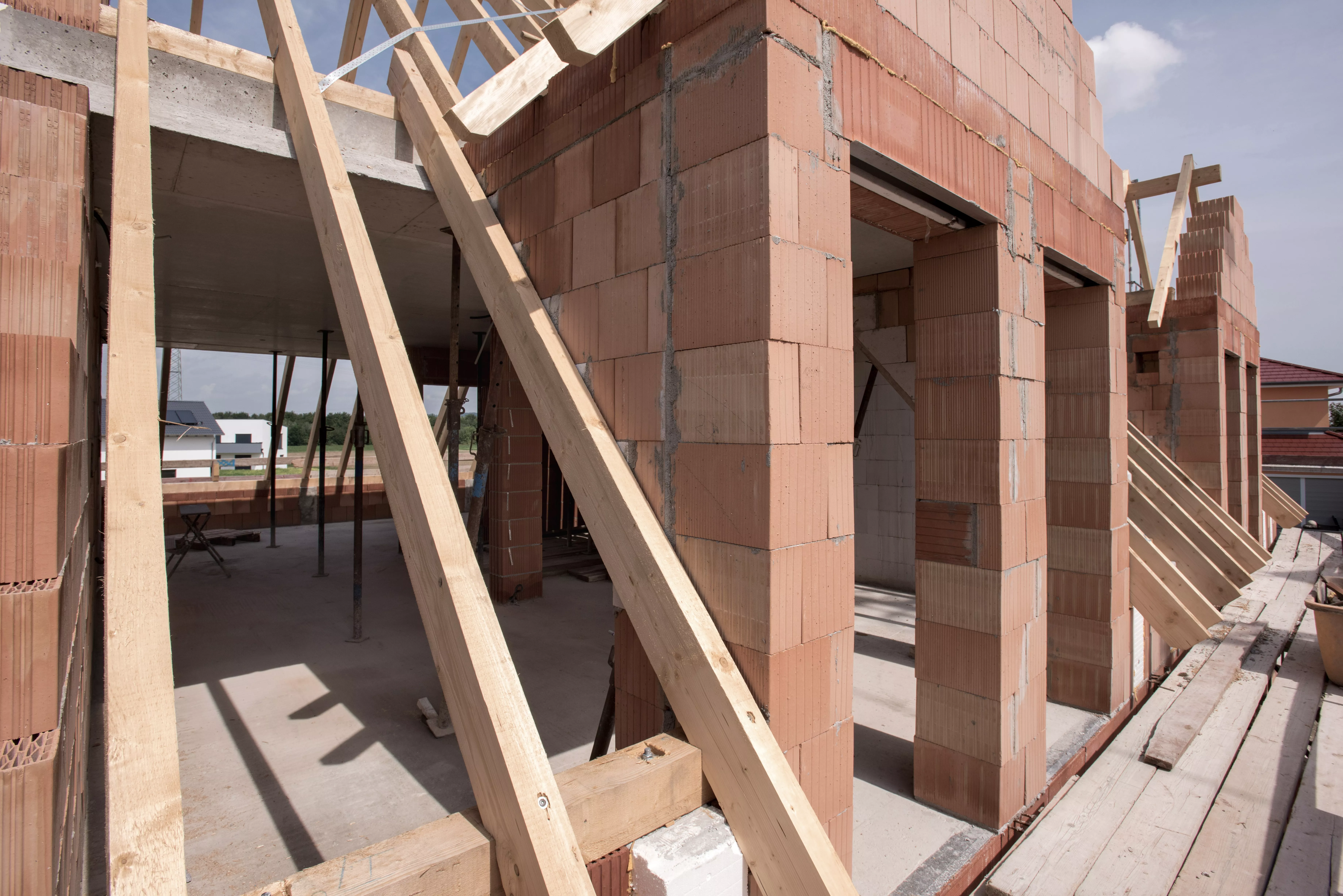 Neubau im Rohbau mit Ziegelmauerwerk, Dachstuhl und Baugerüst